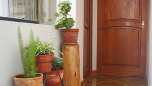 A wooden door with a brass handle, a potted plant on a wooden stool, and several terracotta pots with various plants. - Histórico: 1-bedroom apartment in San Blas market area. Independent living room! (Cusco)