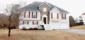 Stunning two-story home with a central entrance, garage, and beautifully manicured yard.