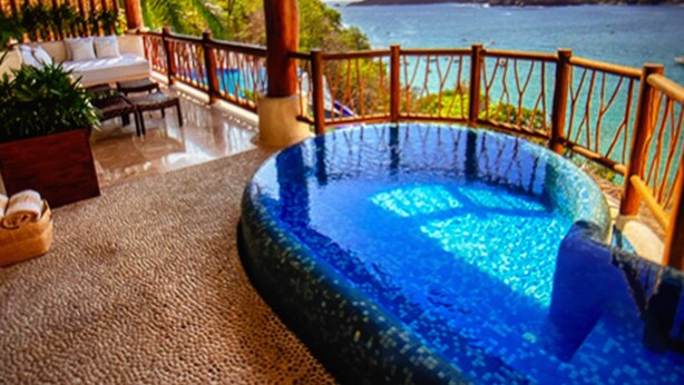 A pool area with a wooden deck, lounge chairs, and a view of the sea. - Luxurious Pacifica Grand Senior Suite (Zihuatanejo)