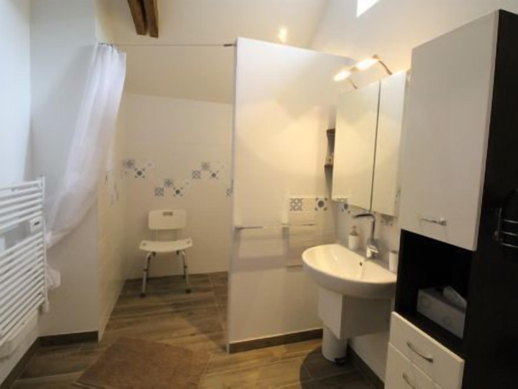 A bathroom with a shower, a toilet, a sink, and a cabinet.