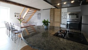 Een moderne keuken met granieten aanrechtbladen, roestvrijstalen apparatuur en een houten trap.