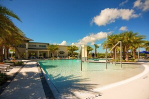 A pool area with a clear blue pool, palm trees, and a building with a modern design. - Relax in Style: Elegant Vacation Home in Orlando (Kissimmee)