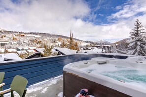 Un jacuzzi con vistas a un pueblo nevado y montañas.