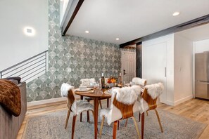 A dining area with a round table, six chairs with white fur trim, and a patterned wallpaper. - KBM Resorts | Aspen Grove | Between Deer Valley and Main St, Awesome views with a Hot Tub, A/C for summer! AGC-8 (Park City)