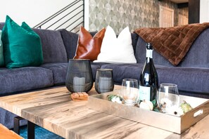 A wooden coffee table with a tray holding a bottle of wine, glasses, and decorative items.