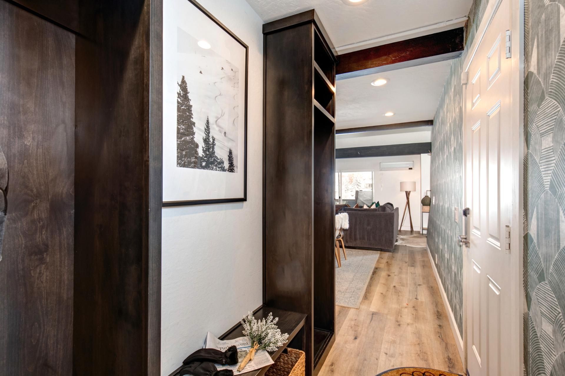 Ein Flur mit Holzboden, einer Bank mit Blumenvase und einem gerahmten Bild an der Wand.