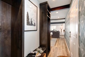 A hallway with wooden flooring, a bench with a vase of flowers, and a framed picture on the wall.
