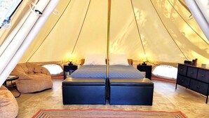 A tent with a bed, two nightstands, a dresser, and a rug.