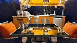 A compact kitchen with a central island, built-in appliances, and orange cushions on the seating.