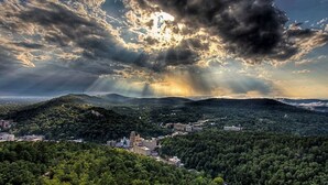 A panoramic view of a city nestled among hills with a mix of urban and natural landscapes.