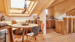 A cozy, wooden interior with a dining area, a kitchen, and a loft bedroom. - Chalet Sunshine – Alpine Charm With Stunning Views (Garmisch-Partenkirchen)