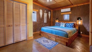 Un dormitorio con una cama de madera, un armario grande y un ventilador de techo.