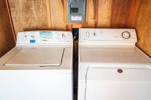 Two front-loading washers with control panels, a power outlet, and a thermostat on the wall. - Unique Strawbale/Hueco Tanks/Mtn Views/King BD (El Paso)