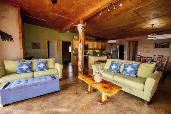 A spacious living area with two sofas, a coffee table, and a kitchen in the background.