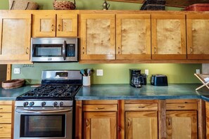 A kitchen with wooden cabinets, a microwave, a stove, and a coffee maker.