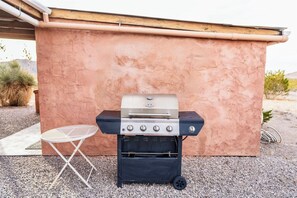 A portable barbecue grill with a control panel and a small table beside it.