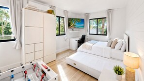 A modern bedroom with a bed, a desk, and a foosball table.