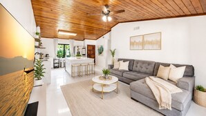A modern living room with a grey sofa, a coffee table, and a ceiling fan. - Charming Nature Farmhouse Getaway – Spacious, Peaceful, Relaxing (Miami)