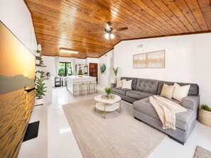A modern living room with a grey sofa, a coffee table, and a ceiling fan. - Charming Nature Farmhouse Getaway – Spacious, Peaceful, Relaxing (Miami)