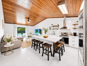 Een moderne keuken met een centraal eiland, barkrukken en een groot raam met uitzicht op een zwembad.