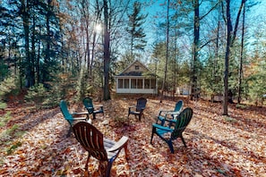 Relax in a serene forest setting, surrounded by tall trees and a cozy cabin with a gabled roof.