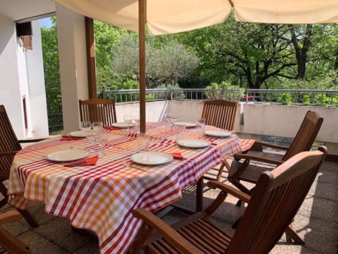 Een terras met een tafel voor vier personen, omringd door houten stoelen.