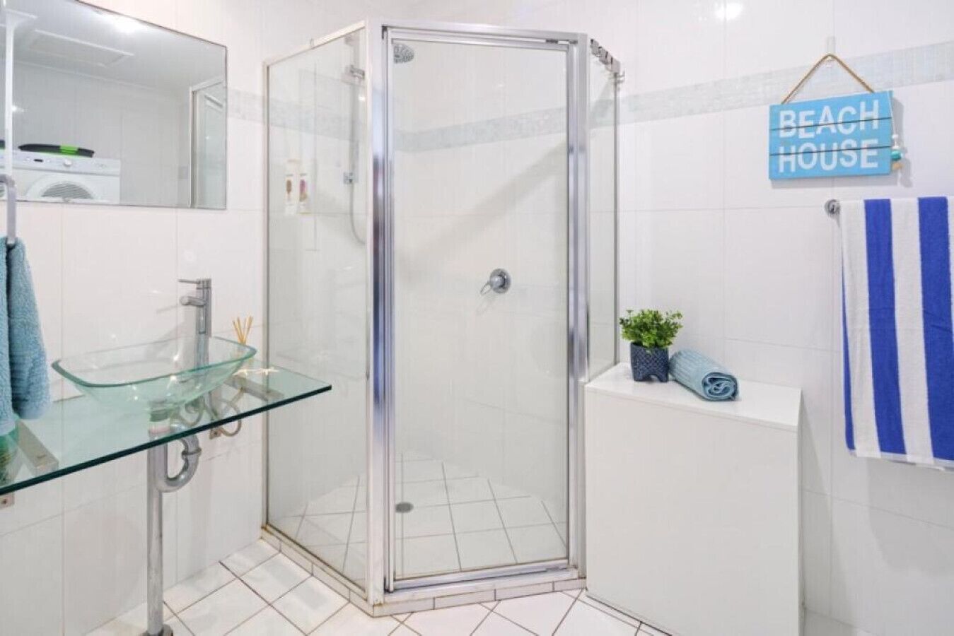 Un baño moderno con cabina de ducha de vidrio, lavabo de vidrio y una toalla azul.