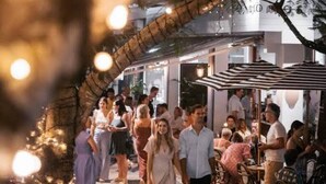 An outdoor dining area with tables and chairs, surrounded by a stone wall and string lights. - Barefoot Buddina Laid-Back Pet Friendly by the Sea (Buddina)