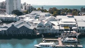 A coastal town with a marina, white buildings, and a large hotel with a prominent tower. - Barefoot Buddina Laid-Back Pet Friendly by the Sea (Buddina)