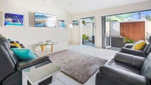 A modern living room with a glass coffee table, leather sofas, and a grey rug. - Barefoot Buddina Laid-Back Pet Friendly by the Sea (Buddina)