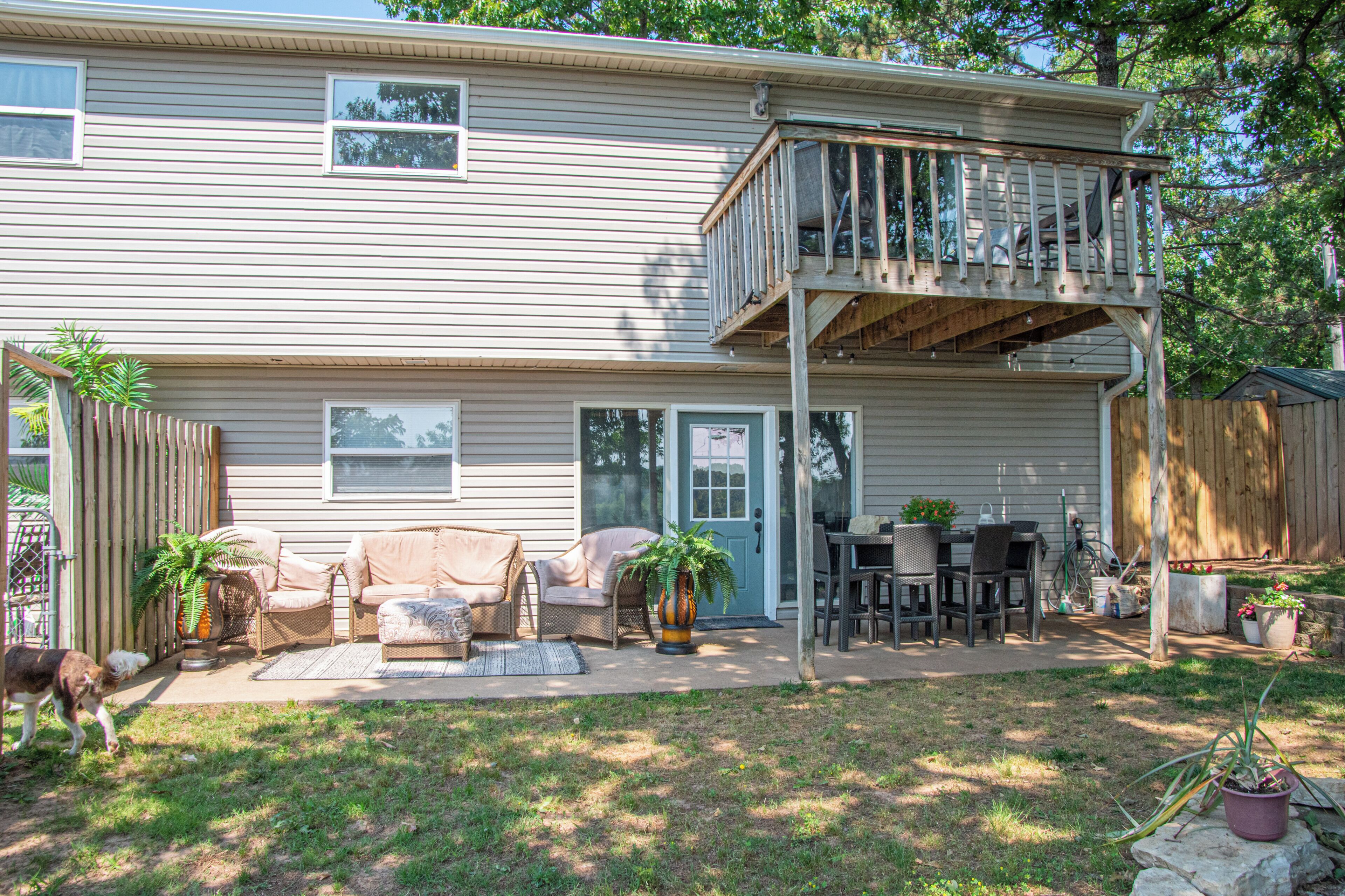 A two-story house with a balcony, outdoor seating area, and a fenced yard.