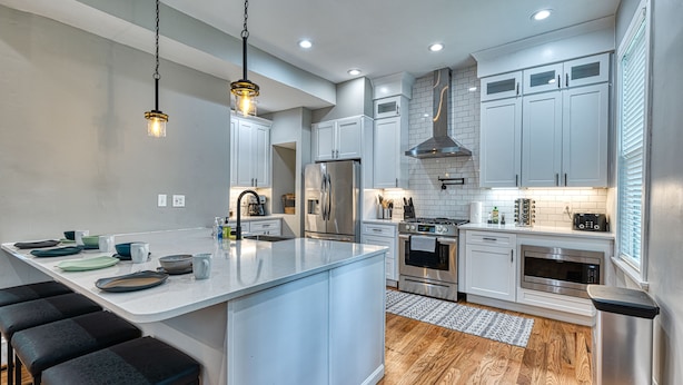 A modern kitchen with white cabinets, stainless steel appliances, and a central island with bar stools.