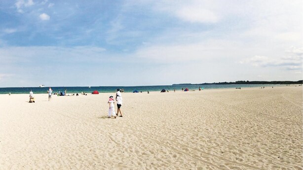 A wide sandy beach with a few tents and people.