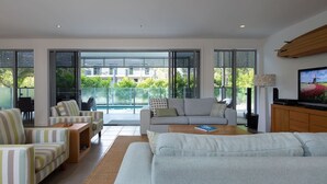 Een moderne woonkamer met een bank, fauteuils, een salontafel en een televisietoestel.