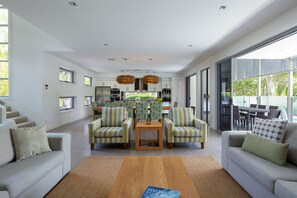 Un grand espace de vie comprenant un canapé, des fauteuils, une table basse et un coin repas avec des chaises.