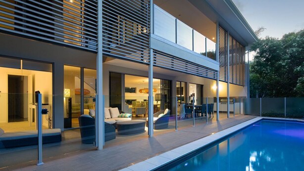 Een modern huis met zwembad, buitenzitplaatsen en een goed verlicht interieur.