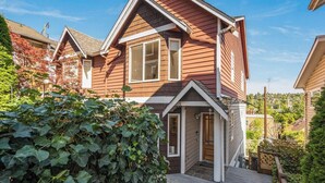 A two-story house with a front porch, a visible garage, and a well-maintained garden. - Perch - Walk to Lake Union! Spacious 3BR/3.5BA w/ Garage (Seattle)
