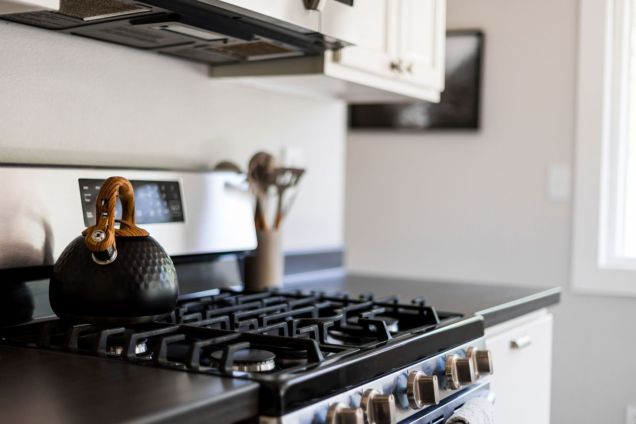 Una cocina equipada con estufa a gas, hervidor y microondas.