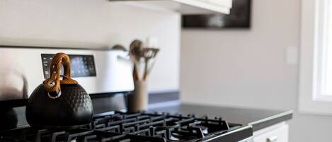 Una cocina equipada con estufa a gas, hervidor y microondas.