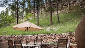 Un patio al aire libre con pared de piedra, una mesa y sillas.