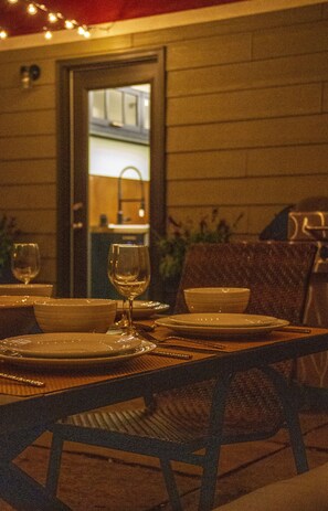 A dining table set with plates, bowls, and wine glasses, with a chair in front. - Brand New - Gracious Old Town Guest House w/ Hot Tub (Fort Collins)