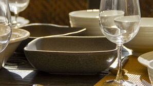 A table set with white plates, bowls, and a wine glass.