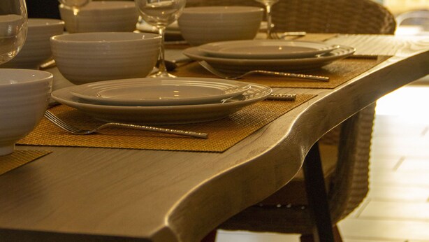 A dining table set with plates, bowls, and wine glasses, with a chair and a placemat.