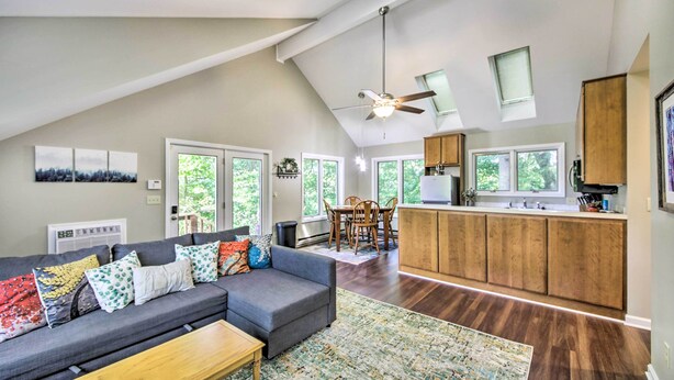 A spacious living area with a gray sofa, a wooden coffee table, and a kitchen with wooden cabinets and a countertop. - Peaceful Nashville Hideaway Near State Parks! (Nashville)
