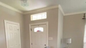 Un salon avec un canapé gris, une table basse blanche et une porte surmontée d’une fenêtre.