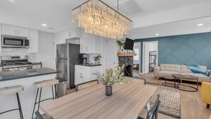 A modern kitchen with a central island, stainless steel appliances, and a hanging light fixture.