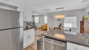 A modern kitchen with white cabinets, a stainless steel refrigerator, and a granite countertop.