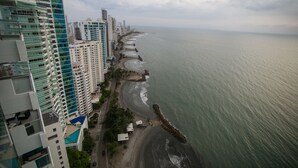 Eine Küstenstadt mit Wolkenkratzern, einem Strand und einem steinernen Wellenbrecher.