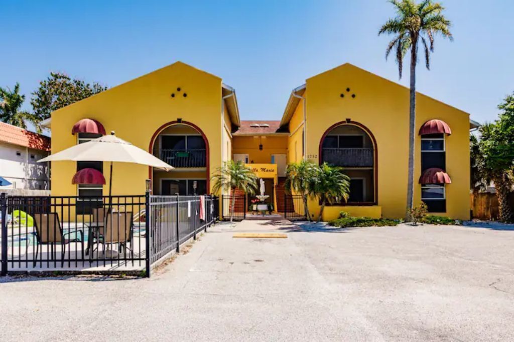 Un bâtiment jaune doté de fenêtres en arc de cercle et d’une enseigne indiquant « Hôtel Maria ».