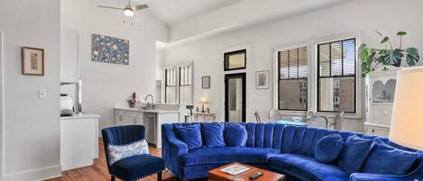 A living room with a blue sectional sofa, a wooden coffee table, and a red patterned rug.